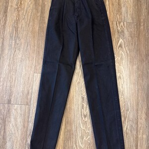 K&ouml;nnte beinhalten: Schwarze Jeans mit hoher Taille und einem Wrangler-Markenetikett. Die Jeans haben eine gerade Beinweite und eine klassische Passform.