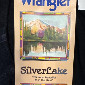 May include: A Wrangler tag with the brand name in blue. The tag features a landscape painting of a lake and mountains, with the text "SilverLake" and the tagline "The most beautiful fit in the West."