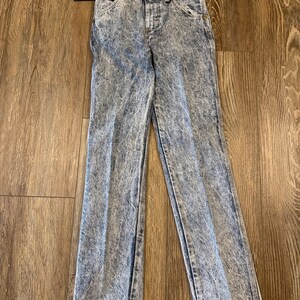 K&ouml;nnte beinhalten: Jeans aus Acid-Wash-Denim mit klassischem F&uuml;nf-Taschen-Design. Die Jeans haben ein hellblaues und wei&szlig;es Marmormuster, einen Knopf- und Rei&szlig;verschluss und ein Etikett am Bund. Die Jeans sind gerade geschnitten.