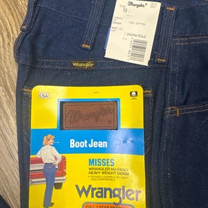 K&ouml;nnte beinhalten: Dunkelblaue Wrangler Bootcut-Jeans mit Etiketten. Die Jeans haben ein klassisches F&uuml;nf-Taschen-Design und ein Wrangler-Etikett auf der Ges&auml;&szlig;tasche. Das Etikett lautet "Misses Wrangler No-Fault Heavy Weight Denim".