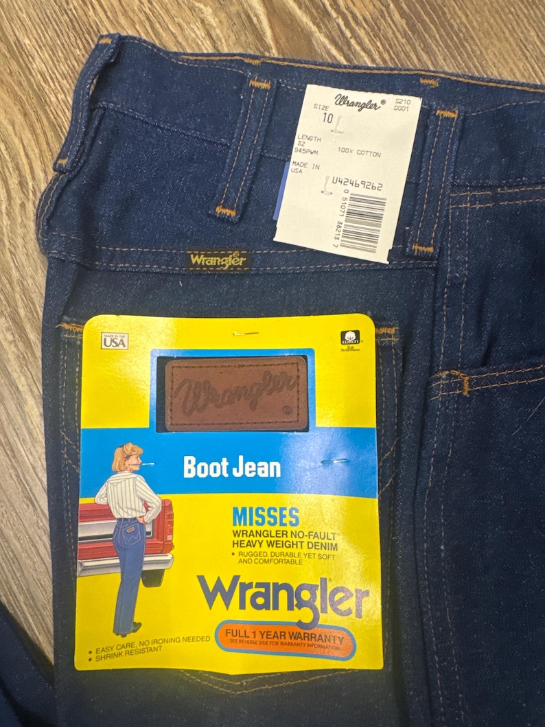 K&ouml;nnte beinhalten: Dunkelblaue Wrangler Bootcut-Jeans mit Etiketten. Die Jeans haben ein klassisches F&uuml;nf-Taschen-Design und ein Wrangler-Etikett auf der Ges&auml;&szlig;tasche. Das Etikett lautet "Misses Wrangler No-Fault Heavy Weight Denim".