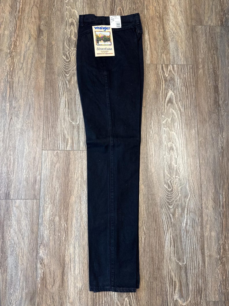K&ouml;nnte beinhalten: Eine schwarze Jeans mit einem Wrangler Silverlake-Etikett. Die Jeans hat eine gerade Passform.