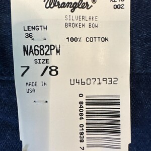 Puede incluir: Una etiqueta blanca con el logo de Wrangler y texto que incluye "SILVERLAKE BROKEN BOW", "100% COTTON" y "SIZE 7/8". La etiqueta tambi&eacute;n indica una longitud de 91 cm y est&aacute; hecha en EE. UU.