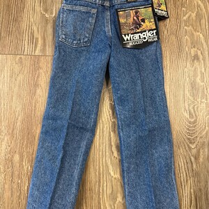 Puede incluir: Un par de pantalones vaqueros azules con una etiqueta de Wrangler en el bolsillo trasero. Los pantalones tienen una pierna recta y un ajuste cl&aacute;sico.