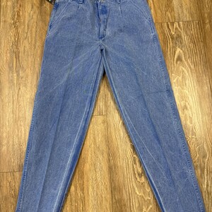 May include: Light blue denim jeans with a faded wash. The jeans have a classic five-pocket design, a button and zipper closure, and a straight leg. A red and white tag is attached to the jeans.
