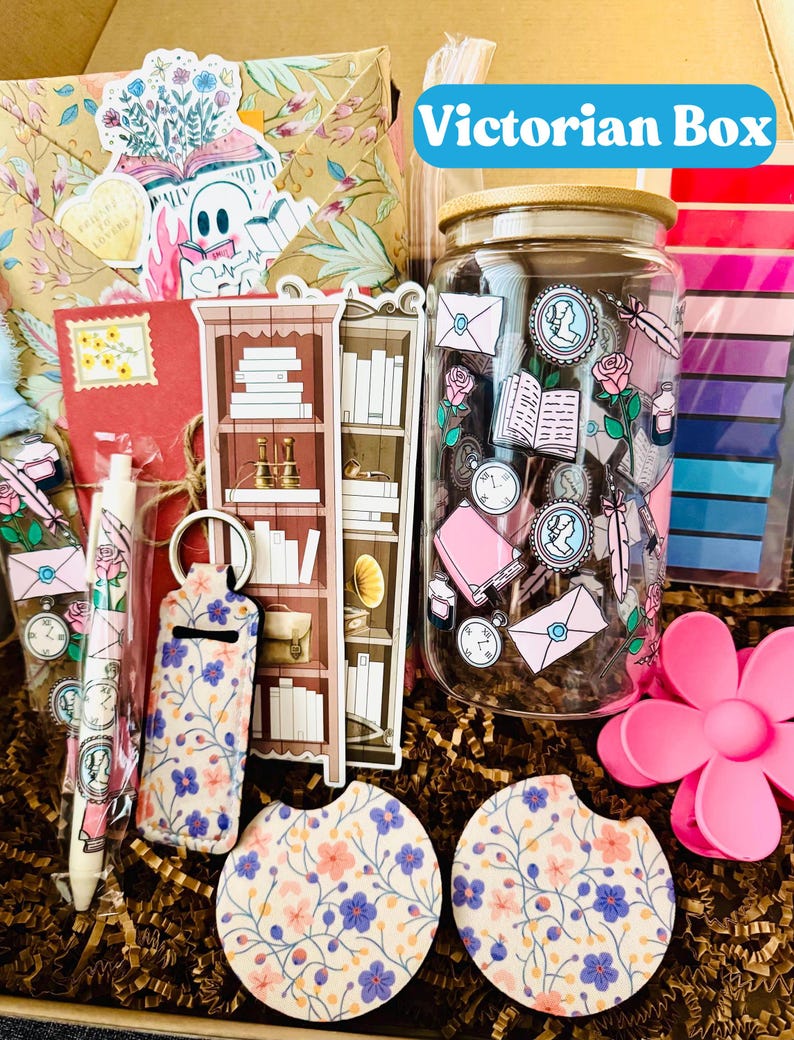 May include: A Victorian Box gift set with a variety of items. Includes a glass jar with a wooden lid, stickers, a pen, a keychain, coasters, and a decorative flower. The box contains a floral patterned envelope and other stationery items.