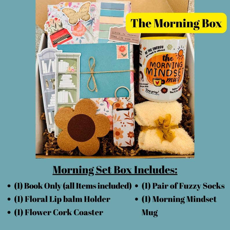 May include: A gift box labeled "The Morning Box" filled with a variety of items. Includes a mug with "Morning Mindset" text, fuzzy socks, a floral lip balm holder, and a flower-shaped cork coaster. Decorative elements include a butterfly and a miniature bookshelf.