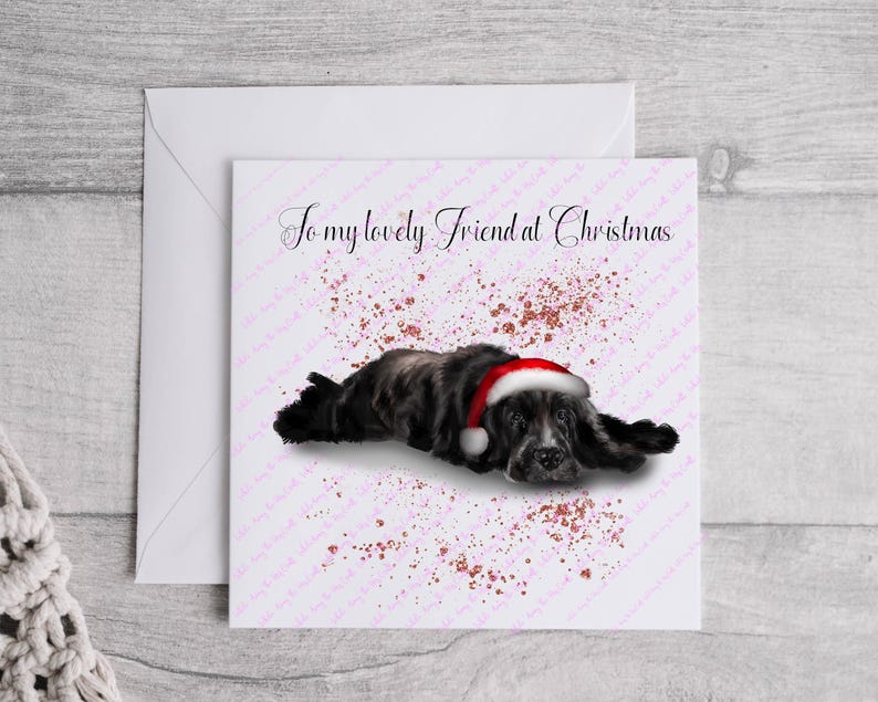 May include: A Christmas card featuring a black and gray dog wearing a Santa hat, with the text "To my lovely Friend at Christmas" in elegant script. The background has a pink speckled design.
