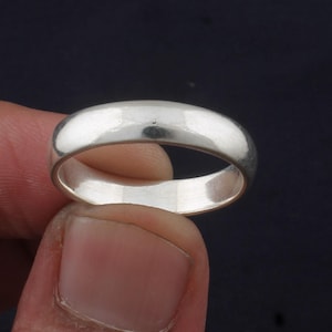 May include: A simple silver band ring with a smooth, polished finish.