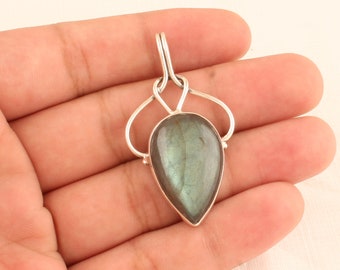 May include: A silver pendant with a teardrop-shaped labradorite gemstone. The pendant has a delicate, ornate design.