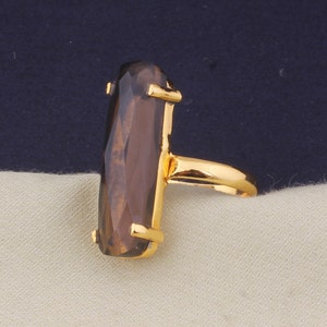 May include: A gold ring with a large, rectangular, faceted, brown gemstone.