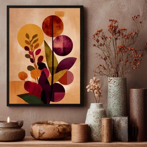 May include: Abstract art print in a black frame. The artwork features a stylized botanical design with circular and leaf shapes in shades of yellow, red, purple, and green against a beige background. Decorative vases and a candle are in the foreground.