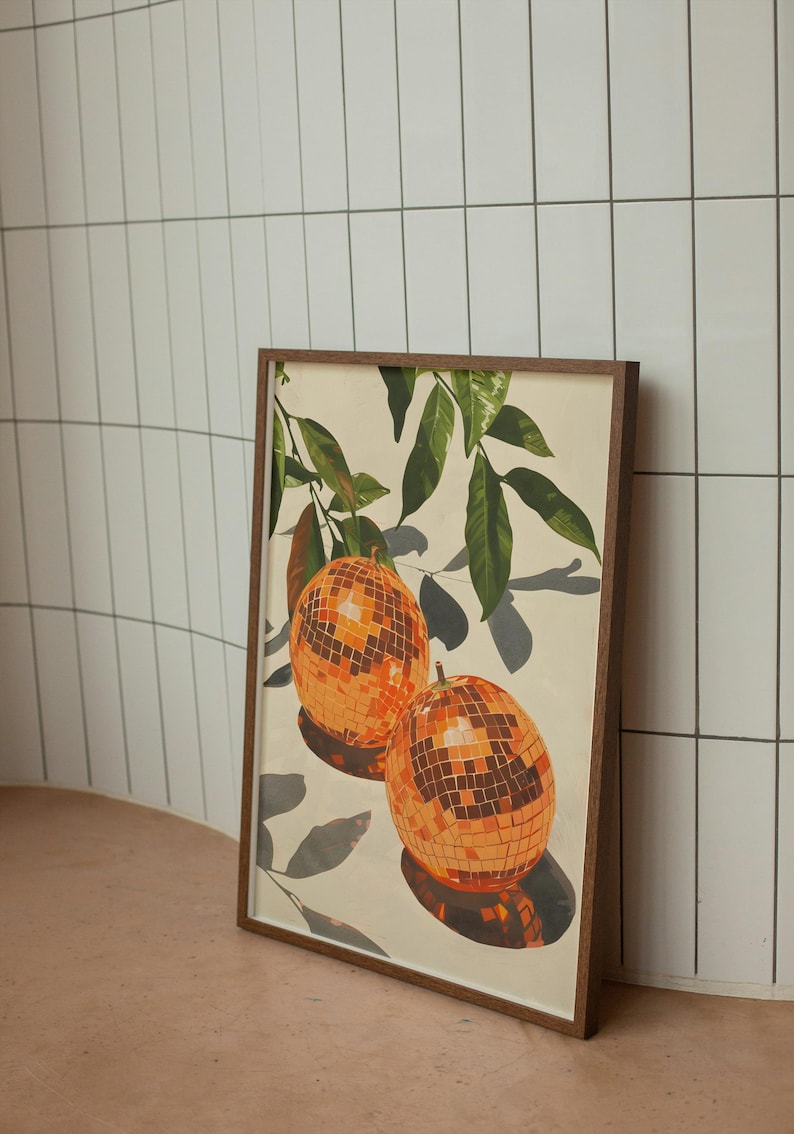 Puede incluir: Una impresi&oacute;n enmarcada de una pintura que representa dos bolas de discoteca naranjas colgando de una rama frondosa. El fondo es de color crema claro.