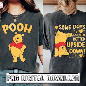 May include: A black t-shirt with a yellow cartoon bear on the front and the word "POOH" in yellow letters. The back of the shirt has a yellow cartoon bear standing on its head with the text "SOME DAYS JUST SEEM BETTER UPSIDE DOWN!" in white letters.