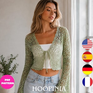 May include: A light sage green crochet cardigan featuring long flared sleeves, a scalloped V-neckline, and a delicate front tie closure. The intricate openwork pattern is crafted with a fine yarn, creating a lightweight, semi-sheer texture.
