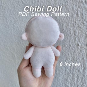 May include: A small, pale pink plush doll with a rounded head and simple limbs. The text "Chibi Doll PDF Sewing Pattern" and "6 inches" is visible. The doll features a smooth, soft texture and a minimalist, featureless face design.