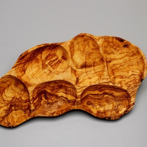 May include: A natural wood serving tray with five separate compartments. The tray is made of olive wood and has a unique, organic shape.