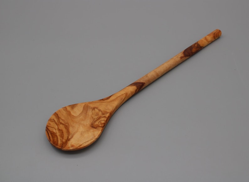 Op de afbeelding: Een houten lepel met een lange steel en een ronde kom. De lepel is gemaakt van olijfhout en heeft een natuurlijke bruine kleur met donkerbruine strepen.