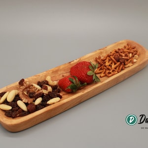 Könnte beinhalten: Ein Holztablett mit drei Fächern, gefüllt mit Mandeln, Rosinen, Walnüssen, Brezeln und Erdbeeren.