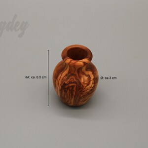 May include: A small, wooden vase with a natural wood grain pattern. It is approximately 6.5 inches tall and 3 inches in diameter.