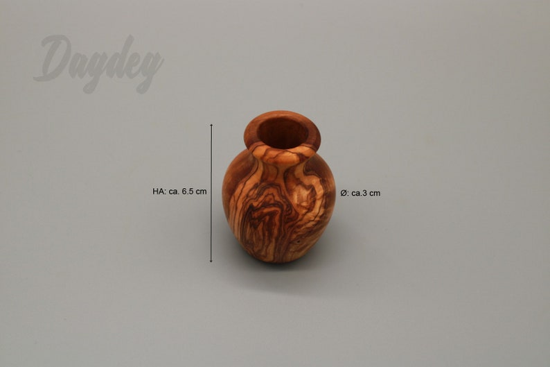 May include: A small, wooden vase with a natural wood grain pattern. It is approximately 6.5 inches tall and 3 inches in diameter.