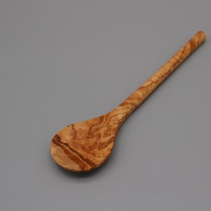 Op de afbeelding: Een houten lepel met een natuurlijk houtnerfpatroon. De lepel heeft een lange steel en een ronde kom.