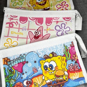 May include: Three rectangular pouches with white trim and zippers. The top pouch has a yellow background with SpongeBob SquarePants and flowers. The middle pouch has a pink background with Patrick Star. The bottom pouch has a blue background with SpongeBob.