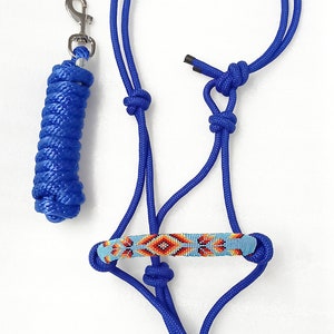 May include: A blue rope halter with a beaded noseband featuring a geometric pattern in orange, red, and blue. The halter is paired with a matching blue rope lead rope with a silver snap hook.