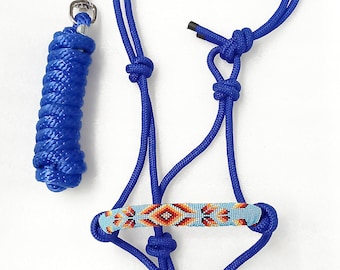 May include: A blue rope halter with a beaded noseband featuring a geometric pattern in orange, red, and blue. The halter is paired with a matching blue rope lead rope with a silver snap hook.