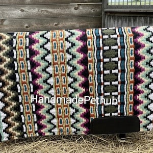 May include: A rectangular horse saddle pad with a black border and a colorful geometric pattern. The pattern includes zigzags and rectangular shapes in shades of green, purple, white, and brown. The text "Handmade Pethub" is visible.