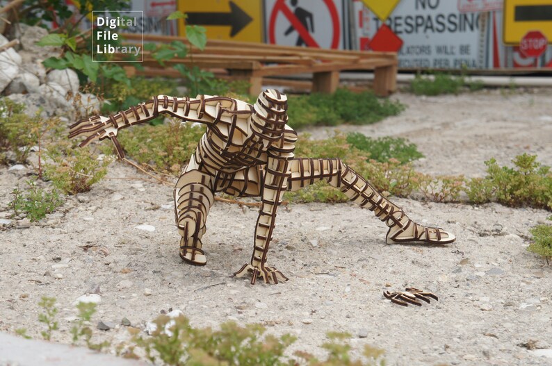 May include: A wooden sculpture of a person in a crouching pose. The sculpture is made of many interlocking pieces of wood, creating a geometric pattern. The sculpture is painted brown and is standing on a light brown surface.