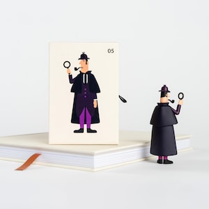 Könnte beinhalten: Eine weiße Karte mit der Nummer 05 darauf gedruckt. Eine Illustration eines Comic-Detektivs, der einen schwarzen Mantel, eine violette Hose und einen Hut mit einer Lupe in der Hand trägt. Der Detektiv hält eine Pfeife im Mund. Eine kleine schwarze Figur eines Detektivs mit einer Lupe in der Hand steht auf einem weißen Buch.