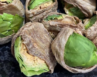 Peut inclure: Gros plan sur une collection d'aliments enveloppés, verts et bruns. Les centres verts sont entourés d'une couche extérieure brune et séchée. Les éléments sont disposés sur une surface sombre et texturée, suggérant une présentation culinaire.