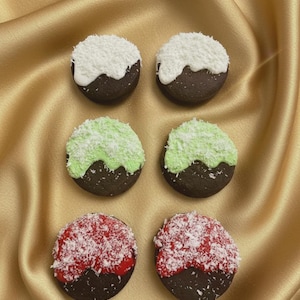 May include: Six round cookies with a dark chocolate base, each topped with a different color of frosting and shredded coconut. The frosting colors are white, green, and red. The cookies are arranged on a gold satin surface.