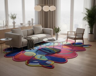 May include: A colorful, abstract area rug with a unique, organic shape. The rug features a vibrant mix of pink, blue, yellow, and green hues. The rug is placed in a modern living room setting with a sofa, chair, and coffee table.