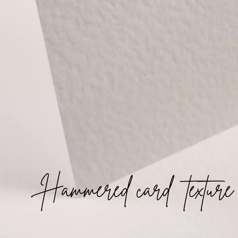 May include: Close-up of a textured, off-white paper surface with the words "Hammered card texture" in cursive script. The paper has a subtle, uneven surface, and the lighting creates soft shadows.