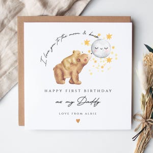 May include: A square greeting card featuring a watercolor illustration of a large brown bear carrying a small bear cub, a smiling moon, and yellow stars. Text reads: I love you to the moon & back, HAPPY FIRST BIRTHDAY as my Daddy, LOVE FROM ALBIE.