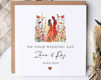May include: A square wedding card featuring a watercolour illustration of a couple in traditional dress amidst flowers. The card displays "ON YOUR WEDDING DAY", the names "Zara & Raj", the date "10.04.2025", and a red heart.