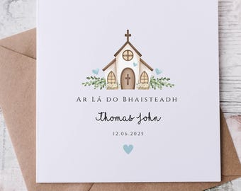 May include: A white card with a watercolor illustration of a church, floral accents, and text. The card reads "AR LÁ DO BHAISTEADH", "Thomas John", and "12.06.2025". The card is inside a brown envelope.