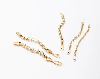 May include: Five gold extension chains for necklaces or bracelets. The chains are different lengths and have a heart-shaped clasp. The text "That might be a good idea! You can have a better look by using birthstone and letter charms on your extension chains." is below the chains. A bracelet with a blue birthstone charm and a gold letter D charm is shown below the text.