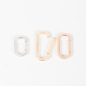 May include: Three metal clasps in different finishes: silver, gold, and rose gold. The clasps are oval shaped and have a spring-loaded gate.