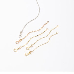 May include: Four gold chain extension pieces in different lengths, with a close-up of a gold chain with a blue birthstone charm attached. "Birthstone or Letter Charms" is written in the image.