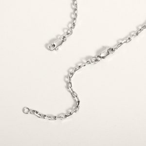 May include: A silver chain necklace with two lobster claw clasps. The chain is made of small, oval-shaped links.