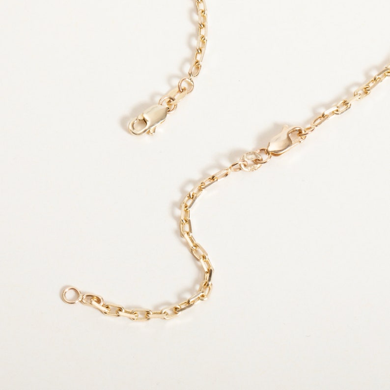 May include: A gold chain necklace with a lobster clasp closure. The chain is made of small, linked oval shapes.
