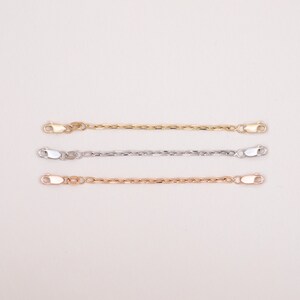 May include: Three gold chain extenders, one in yellow gold, one in white gold, and one in rose gold. Each extender has a lobster clasp on each end.