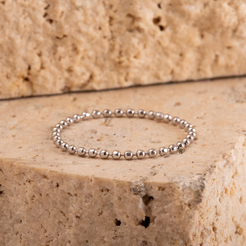 K&ouml;nnte beinhalten: Ein silbernes Armband mit Perlenkette.