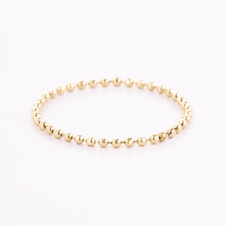 A gold chain ring with small, round beads.