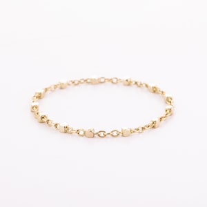 May include: A delicate gold chain ring with small square-shaped links.