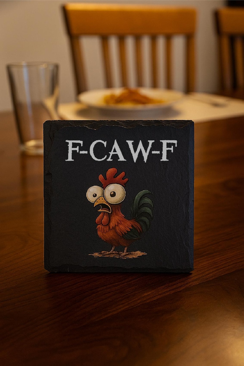 May include: Black square coaster with the text "F-CAW-F" in white. The coaster features a cartoon rooster with large eyes and a surprised expression. The rooster is primarily red and brown with a green tail.