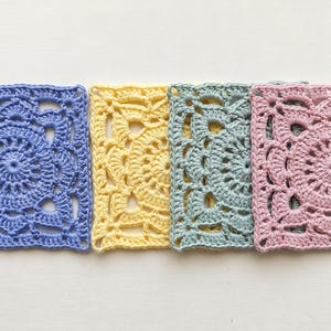 May include: Four square crochet motifs arranged in a horizontal row. Each piece features a circular floral pattern worked into a square shape. The colors from left to right are periwinkle blue, pale yellow, sage green, and soft pastel pink.